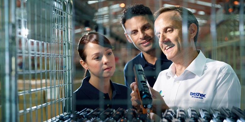 Two men and a woman looking at a toner cartridge