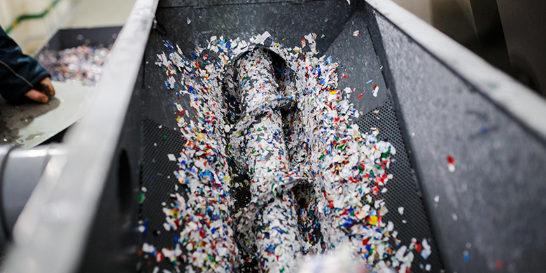 Grey drill grinding down white, blue, yellow and green paper 