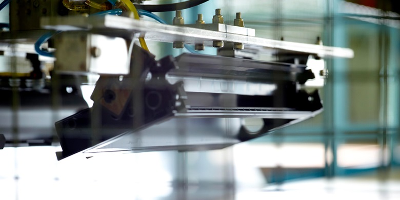 Top part of a machine in a factory with bars in the foreground